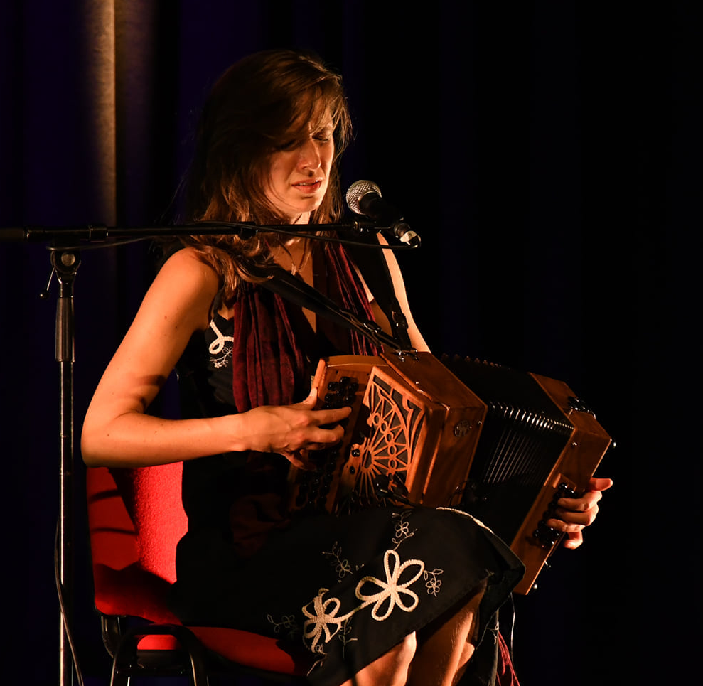Eva Parmenter playing diatonic accordion on stage.